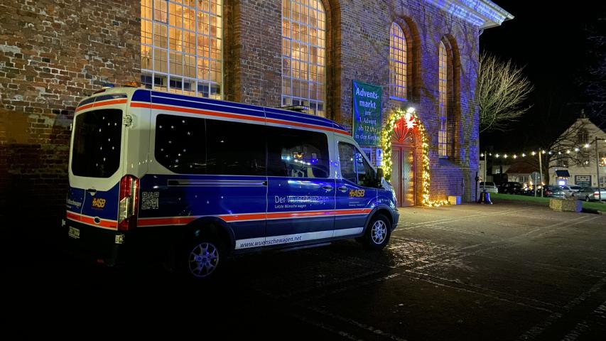 Der Wünschewagen vor der hell erleuchteten Kirche